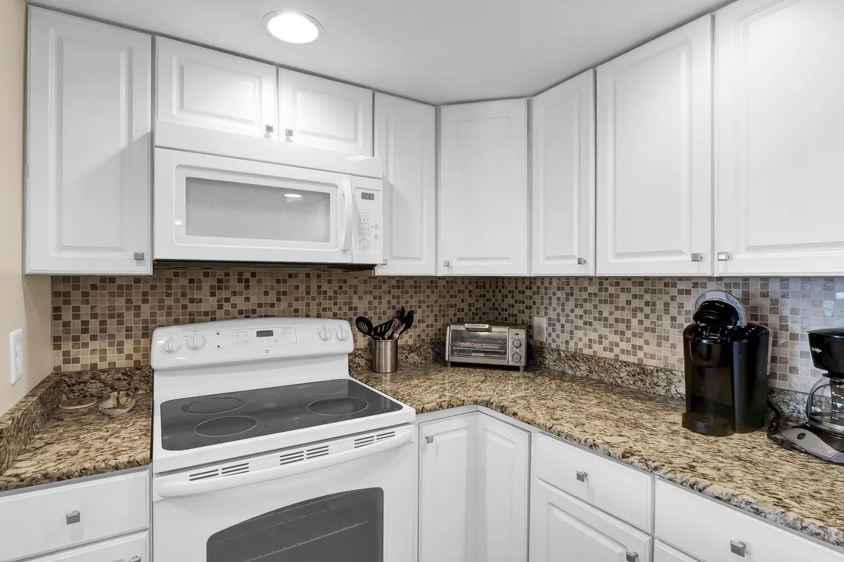 A close-up of the kitchen workspace featuring a stove, microwave, coffee maker, and generous countertops. The inviting setup encourages both casual cooking and preparing larger meals, with plenty of space for family members to gather or collaborate.